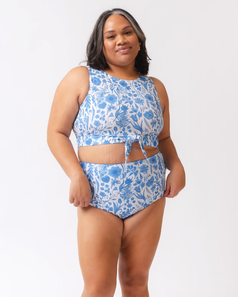 Woman wearing a blue floral two-piece swimsuit on a white background