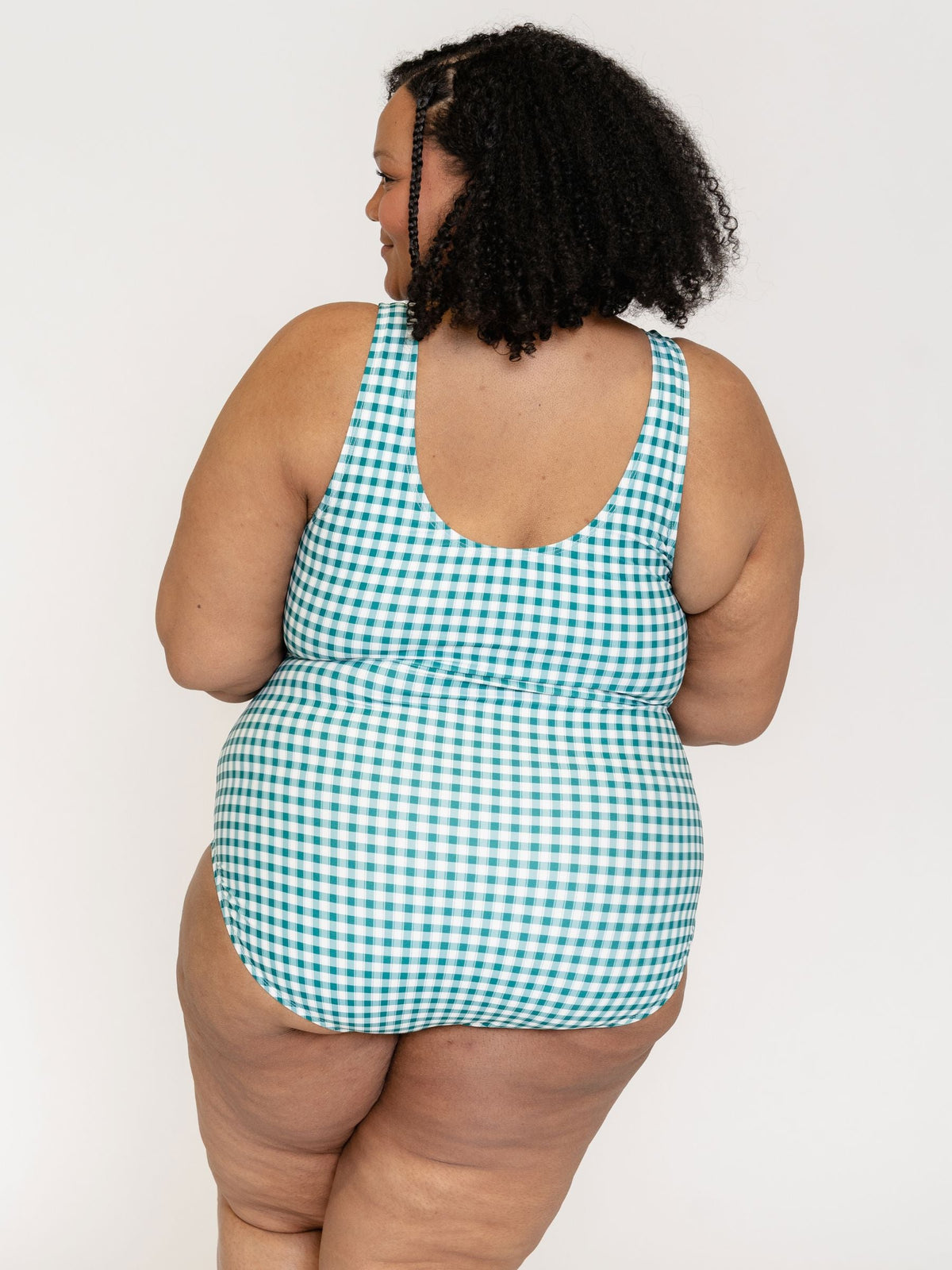 Person wearing a green and white checkered swimsuit against a plain background