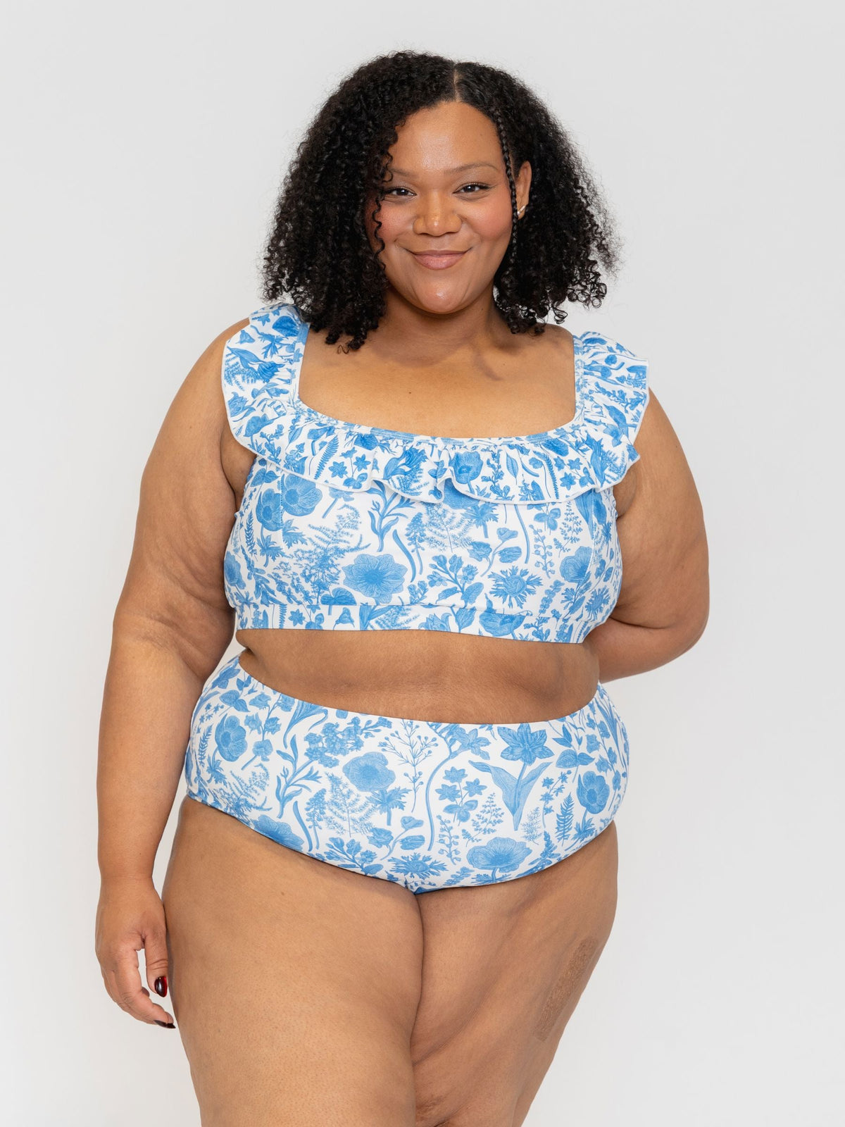 Woman wearing a blue floral two-piece swimsuit against a white background