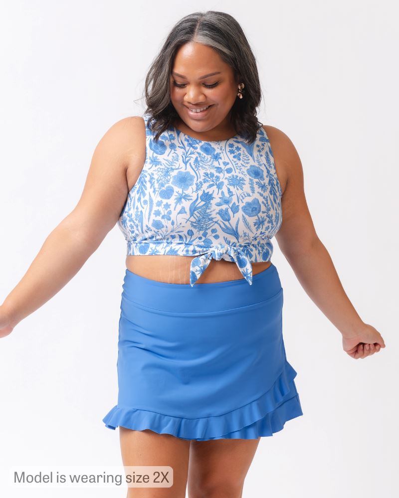 Woman wearing a blue floral top and blue skirt on a white background