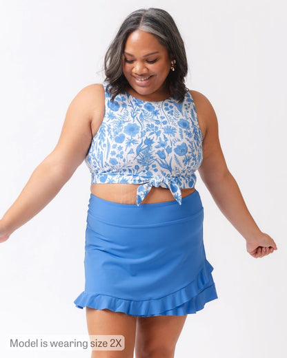 Woman wearing a blue floral top and blue skirt on a white background
