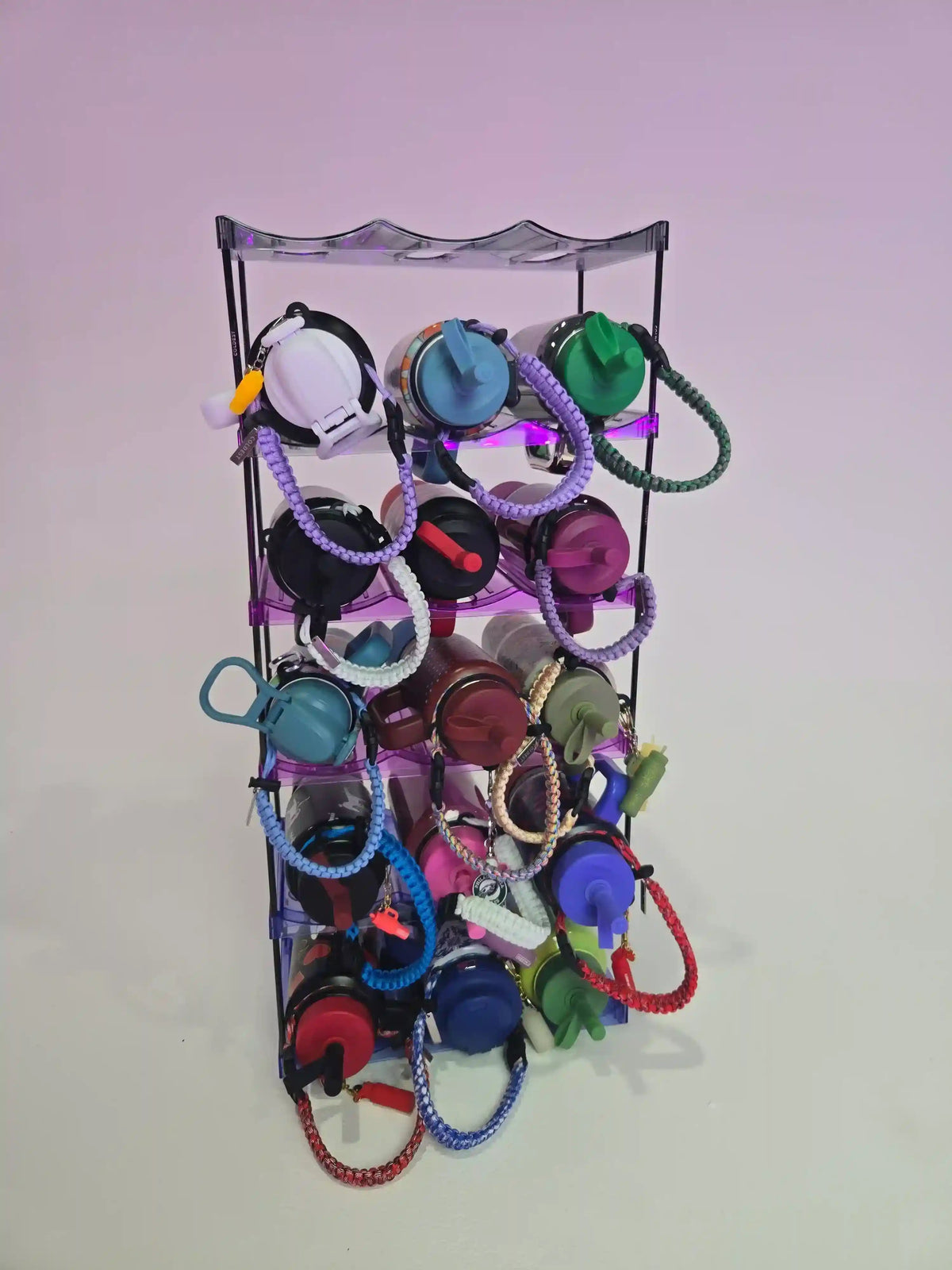 Metallic keychain display rack with various colorful keychains on a light purple background
