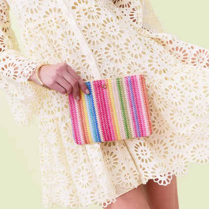 Hand holding a colorful striped pouch against a light background