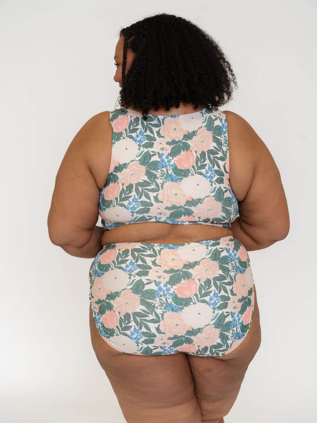 Person wearing a floral two-piece swimsuit against a white background