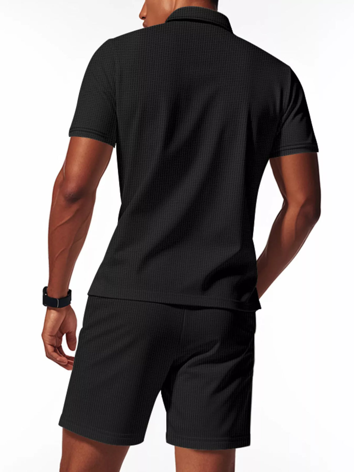 Man wearing a black textured polo shirt and shorts on a white background