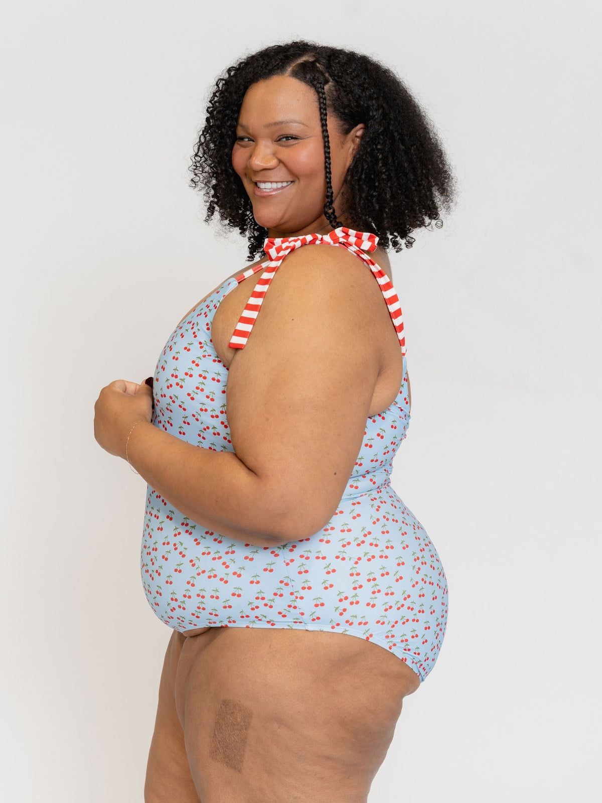 Woman wearing a blue floral swimsuit with a red and white striped tie on a plain background