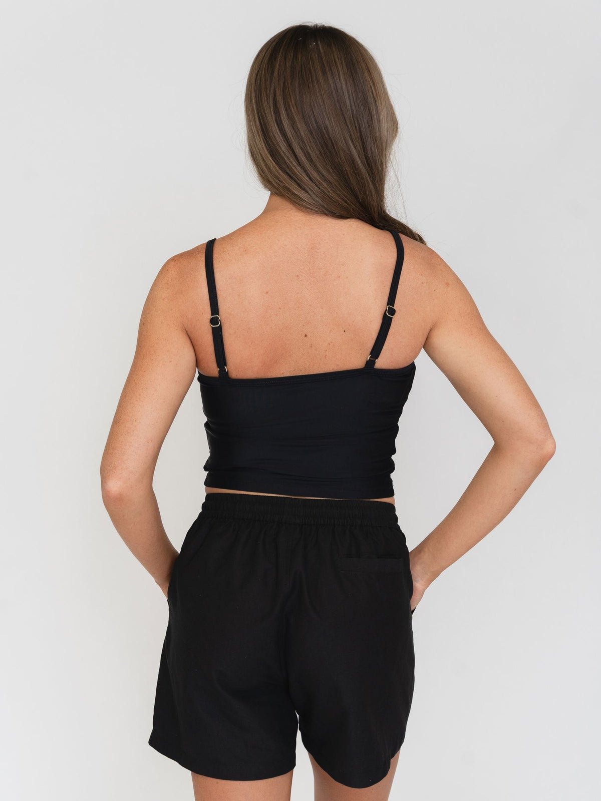 Woman wearing a black tank top and shorts set on a plain background