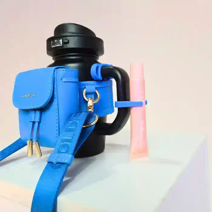 Black water bottle with a blue holder and pink straw on a light background