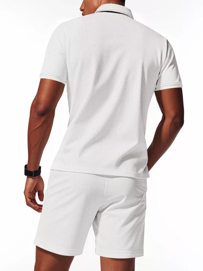 Man wearing a white textured polo shirt and shorts set on a white background
