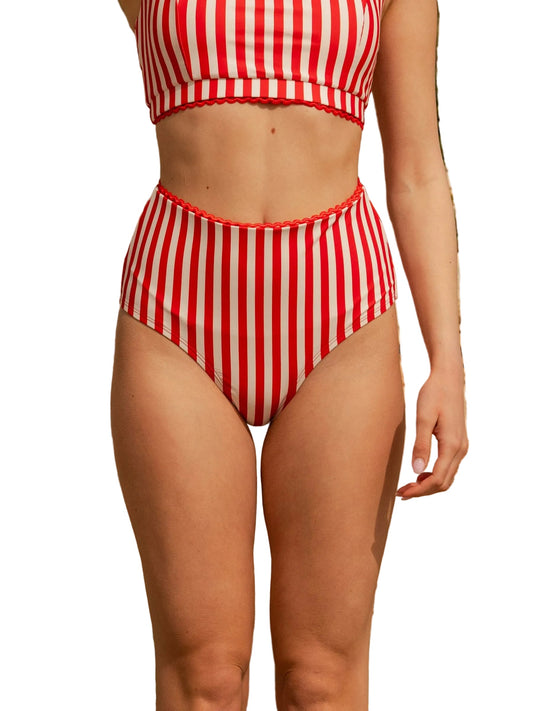 A model wearing a two-piece bikini with red and white vertical stripes, featuring a cropped top and high-waisted bottoms, shown against a plain white background.