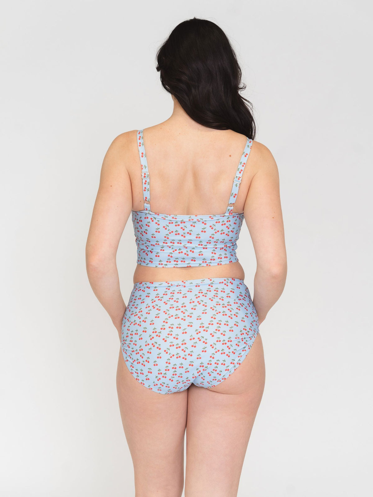 Woman wearing a light blue patterned bikini set on a plain background