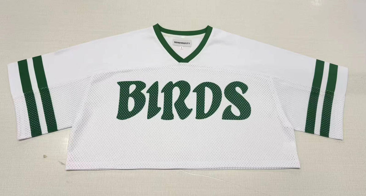 White sports jersey with green accents and 'BIRDS' text on a beige background