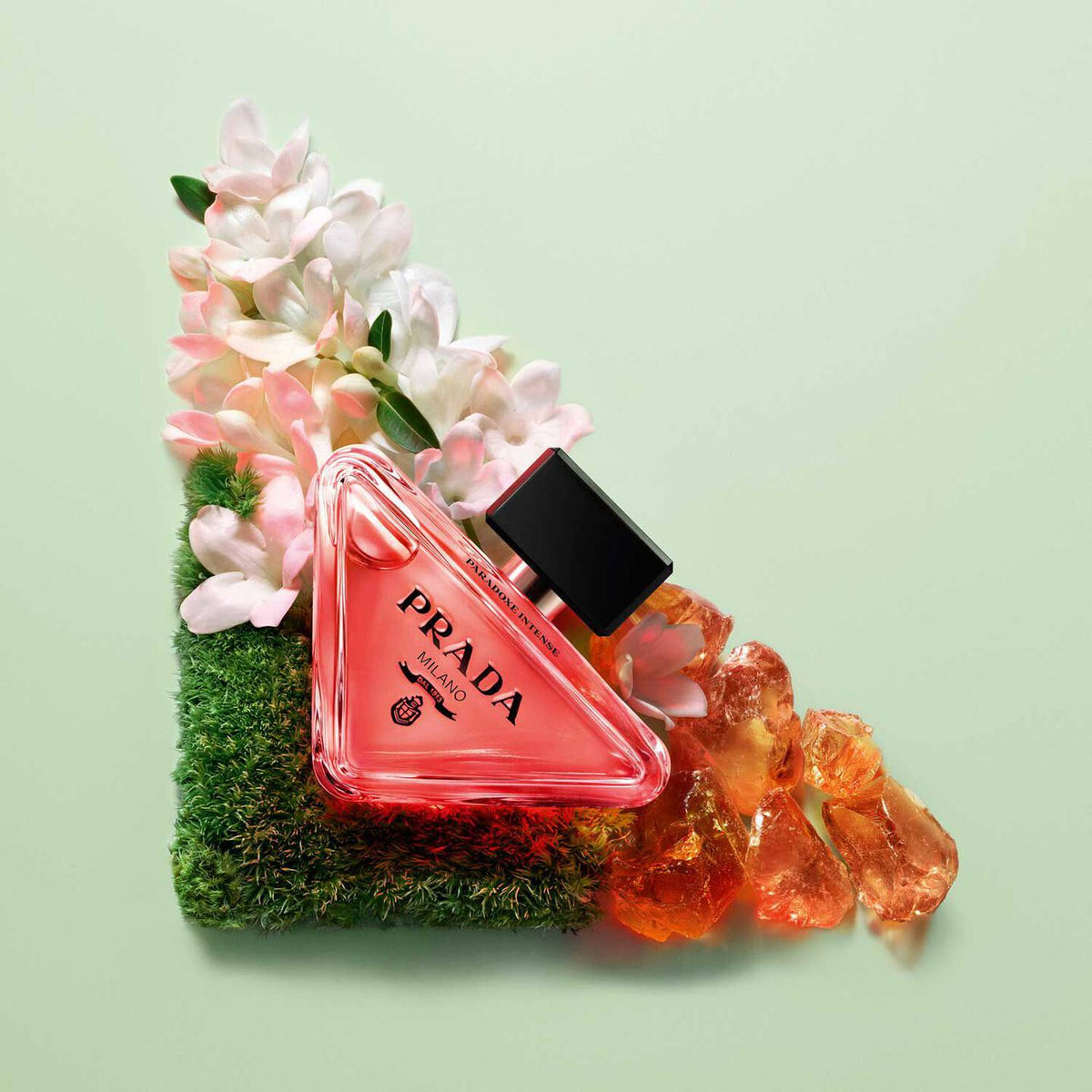 Prada perfume bottle with flowers and decorative elements on a light green background