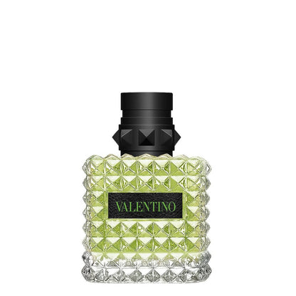A bottle of Valentino fragrance with a textured, faceted clear glass body showing light green liquid inside, a black cap with a geometric design, and a black label with green 'VALENTINO' text, set against a plain white background.