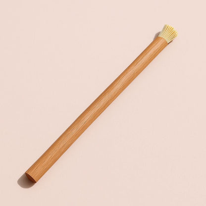 Wooden whisk with bamboo handle on a beige background