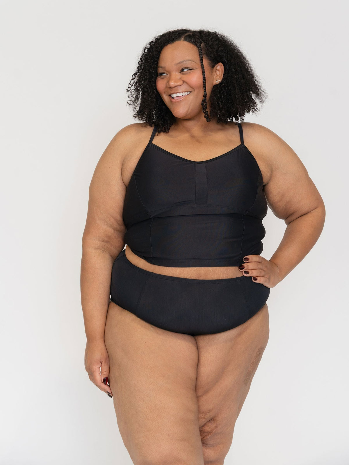 Woman wearing a black two-piece swimsuit against a white background