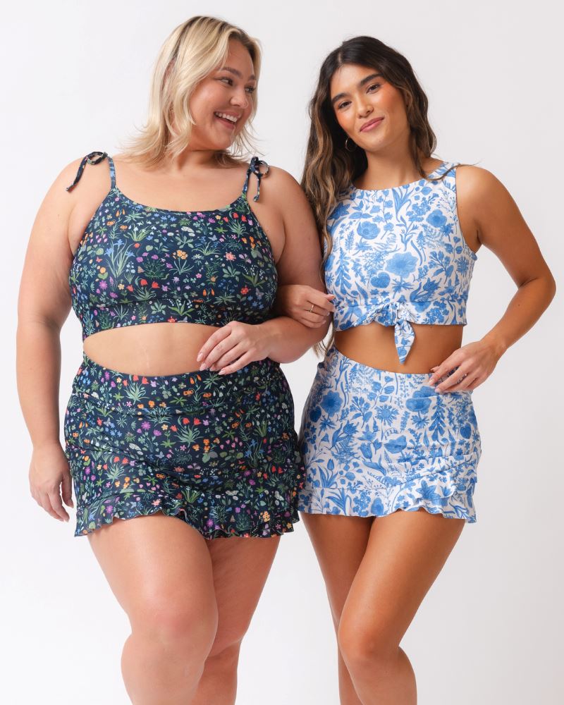 Two women wearing floral two-piece swimsuits on a white background