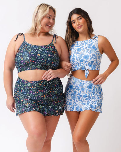 Two women wearing floral two-piece swimsuits on a white background