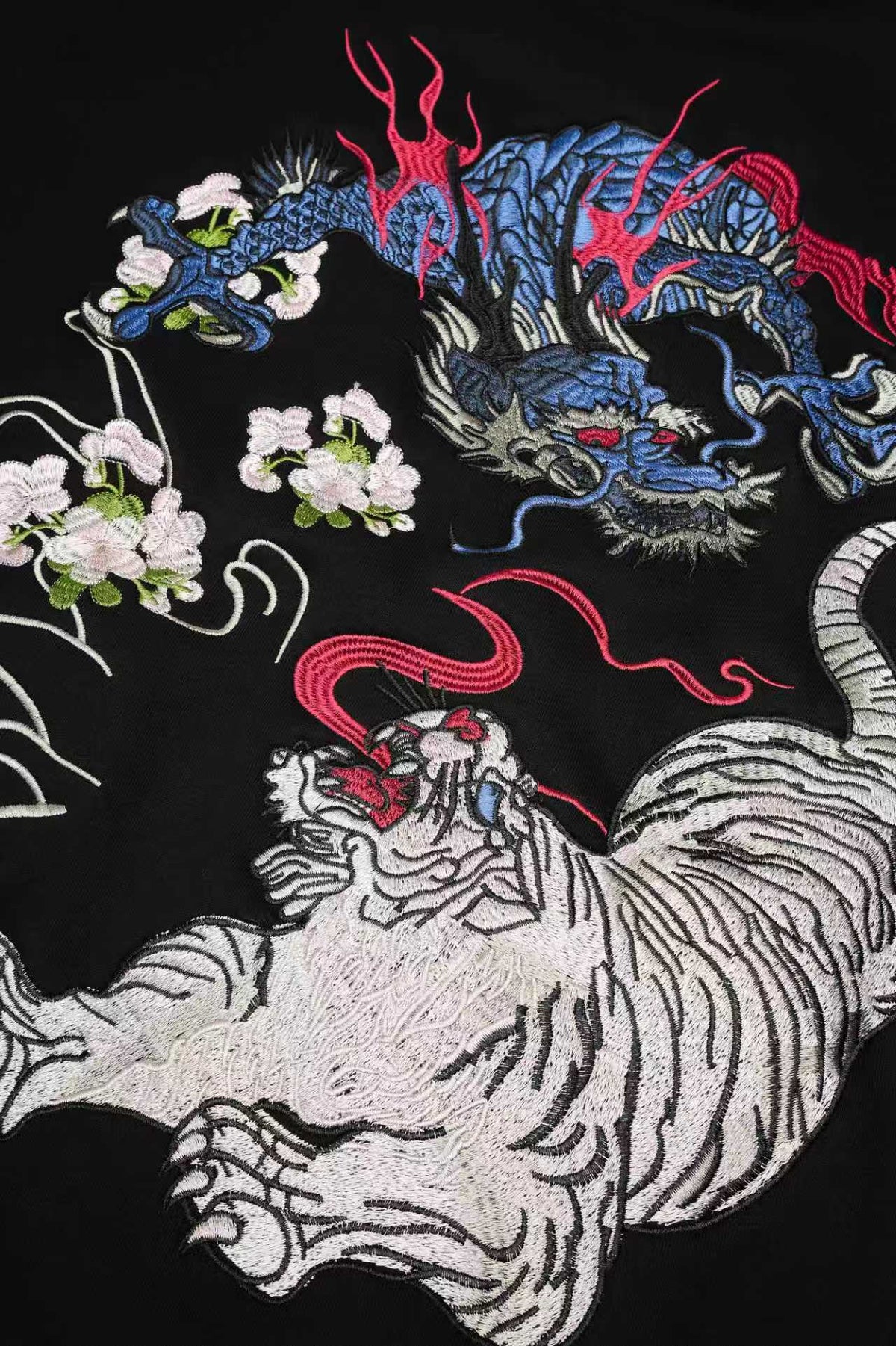 Embroidered design featuring a dragon, tiger, and flowers on black fabric.