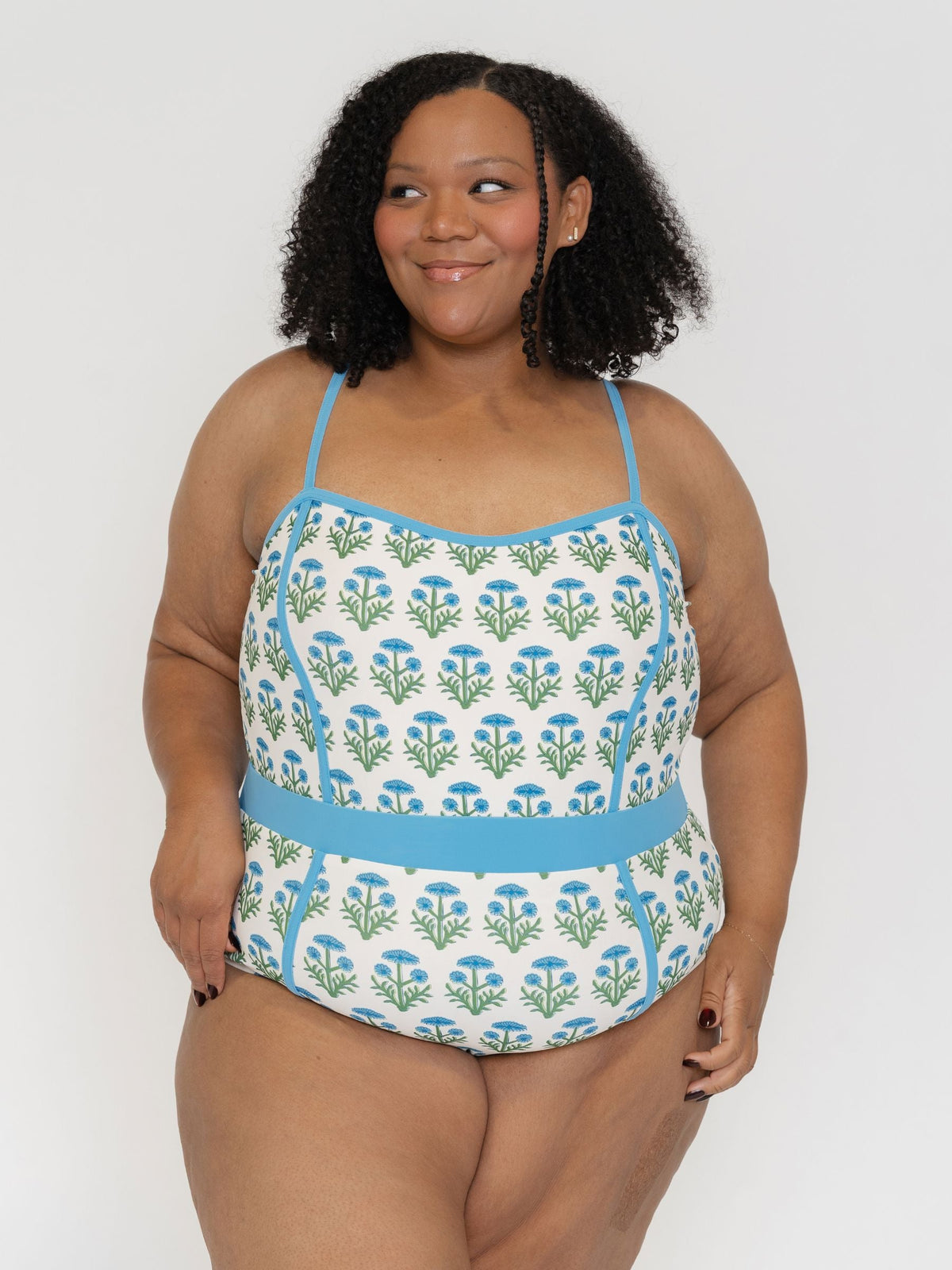 Woman wearing a floral-patterned swimsuit with blue straps against a white background