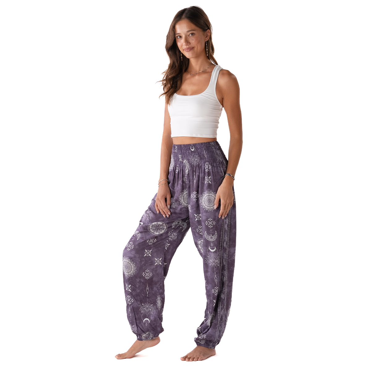Woman wearing purple patterned pants and a white top on a white background
