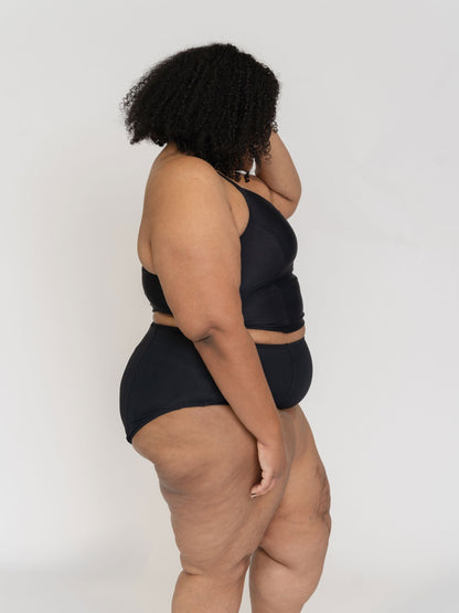 Woman wearing a black bikini set against a plain background