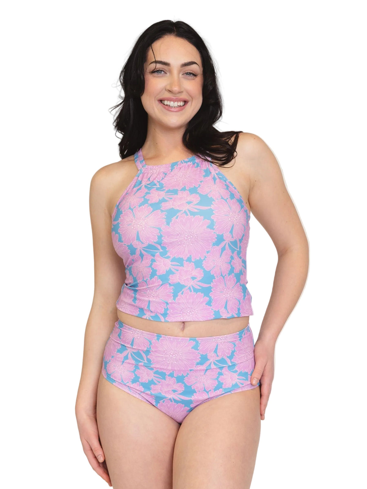 A woman modeling a two-piece swimsuit with a pink and light blue floral pattern against a solid white background.