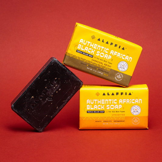 Two bars of Alaffia Authentic African Black Soap on a red background