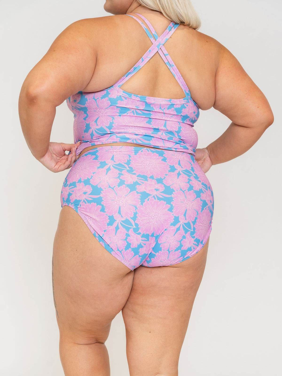 Woman wearing a pink and blue floral swimsuit against a white background