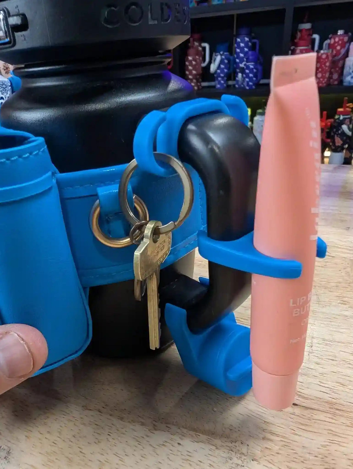 Blue holder with keys and a bottle on a wooden surface