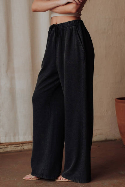 Person wearing black wide-leg pants against a neutral background