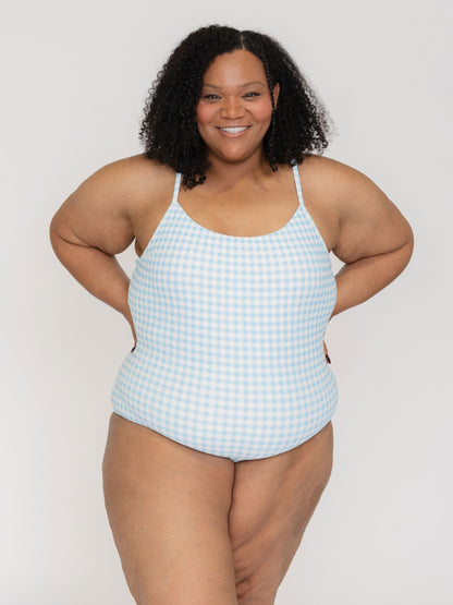 Woman wearing a blue and white checkered swimsuit against a plain background
