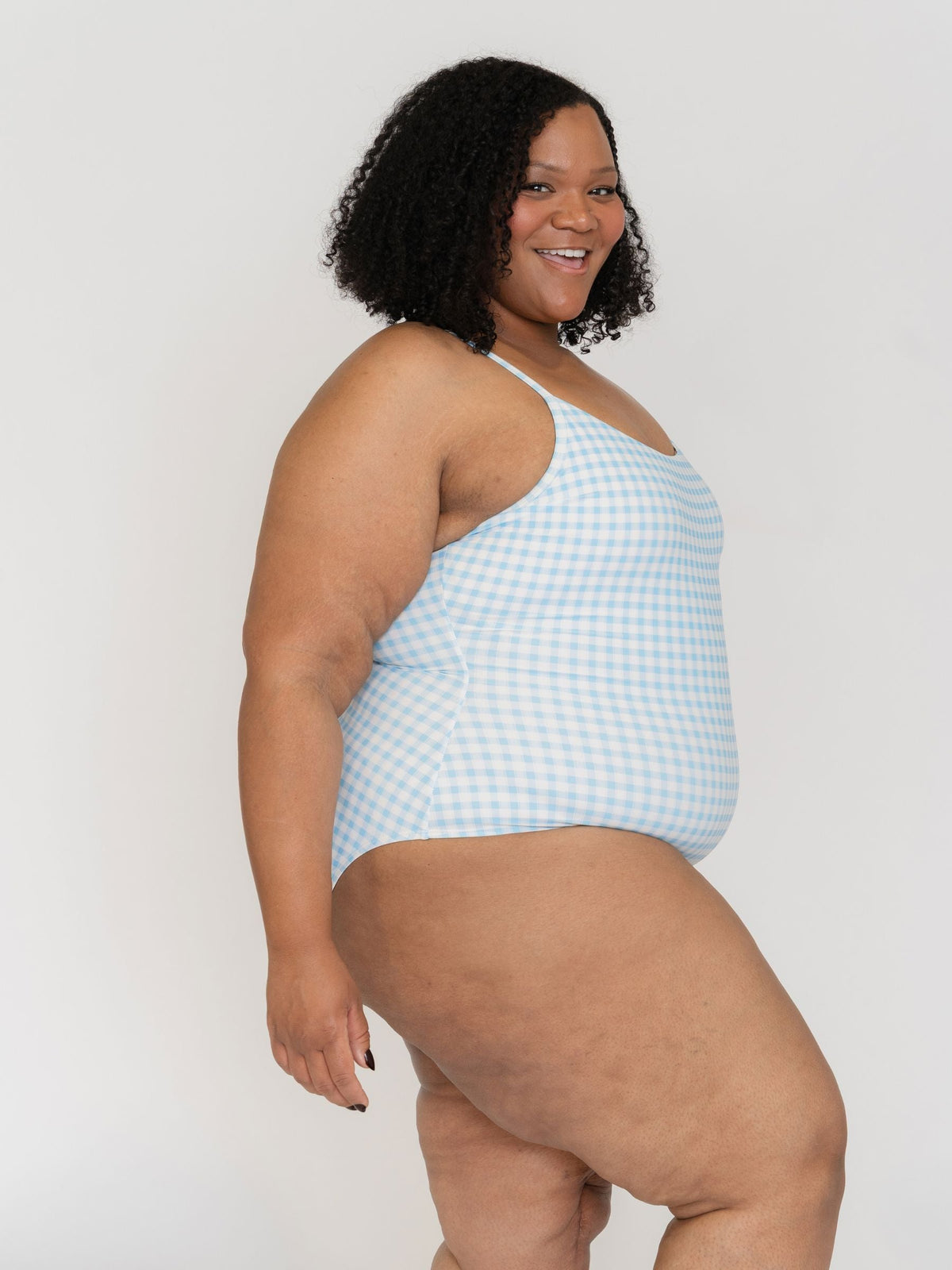 Woman wearing a light blue checkered swimsuit against a white background