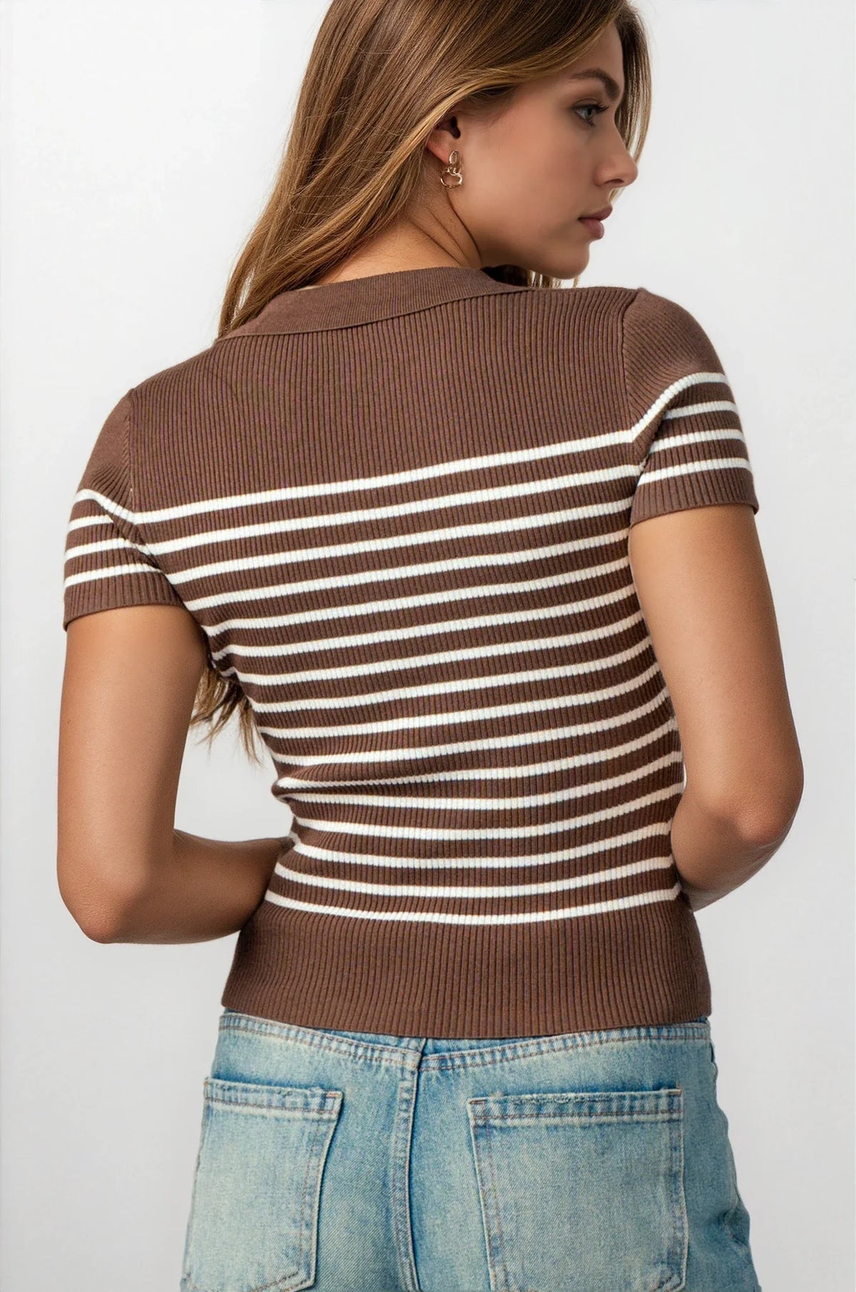 A woman shown from the back wearing a brown short-sleeve ribbed knit top with thin white horizontal stripes, paired with light blue jeans, against a plain white background.