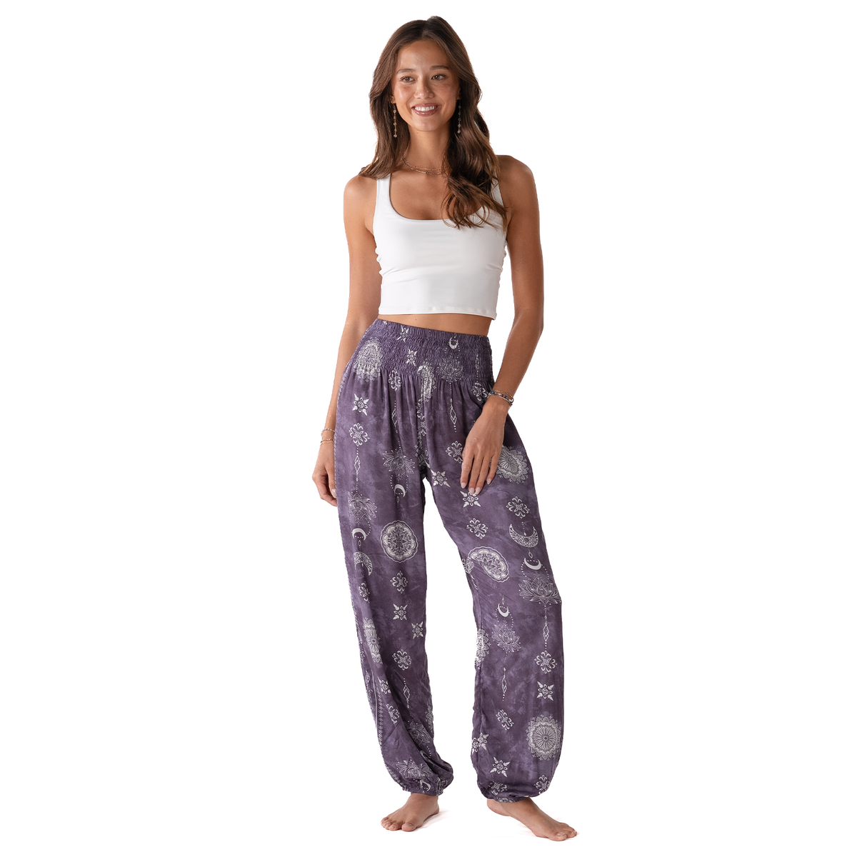 Woman wearing purple patterned pants and a white top on a white background