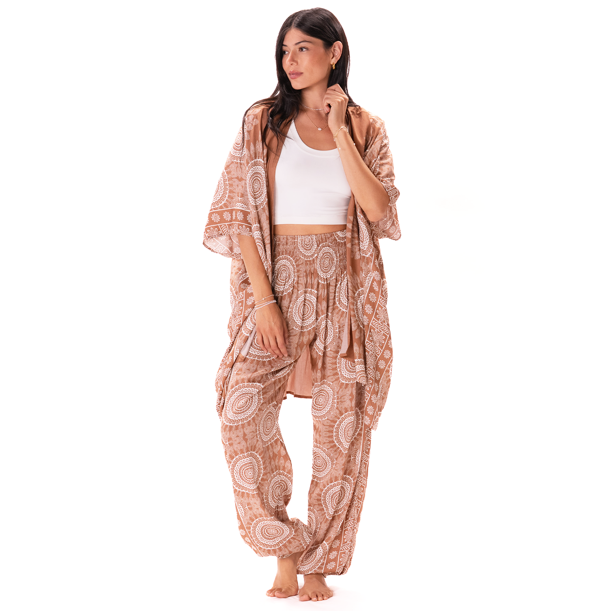 A woman modeling a matching bohemian two-piece set consisting of a white crop top and a rust-orange and cream paisley print harem pants with a matching open-front cardigan, set against a plain white background.