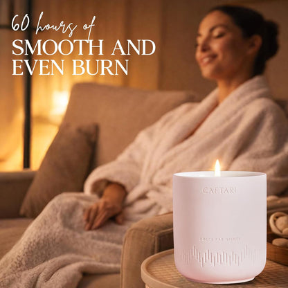 Lit Dolce Far Niente candle in a living room, with a woman seated on a couch behind it