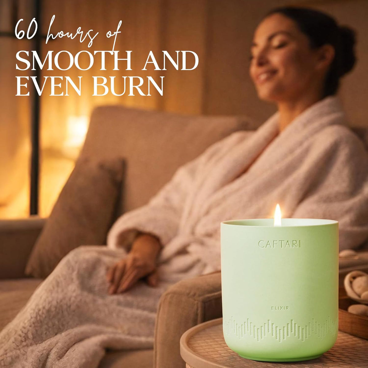 Elixir Bergamot Scented Candle in green ceramic on a table, with a woman in a robe seated on a couch behind it