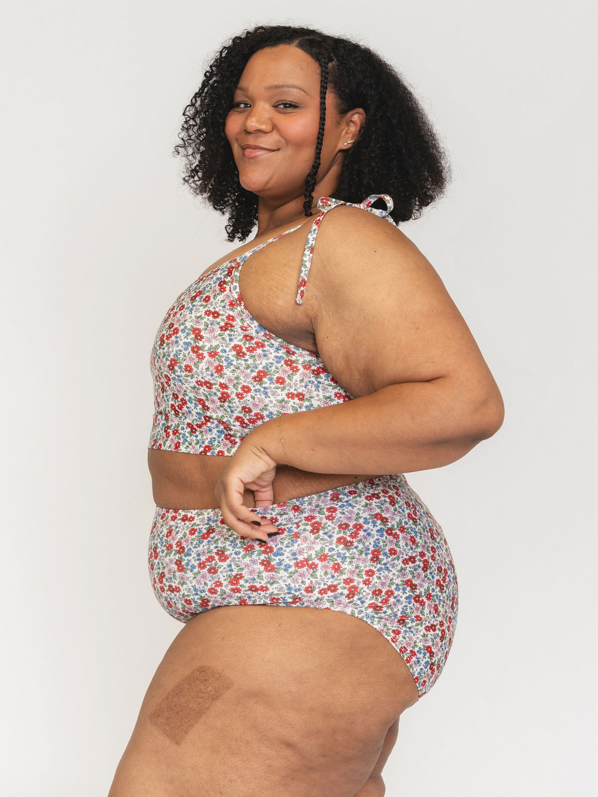 Woman wearing a floral one-piece swimsuit against a plain background