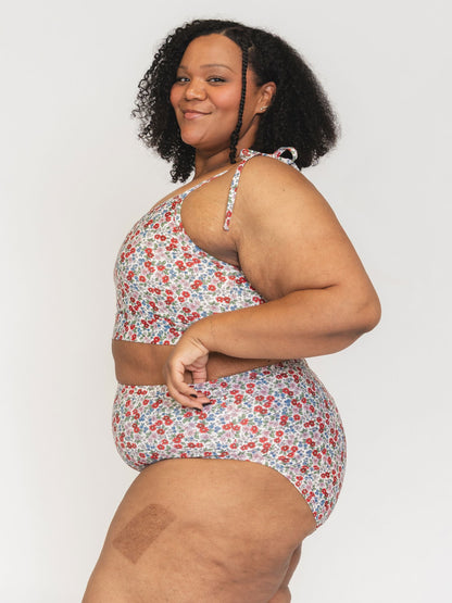 Woman wearing a floral one-piece swimsuit against a plain background