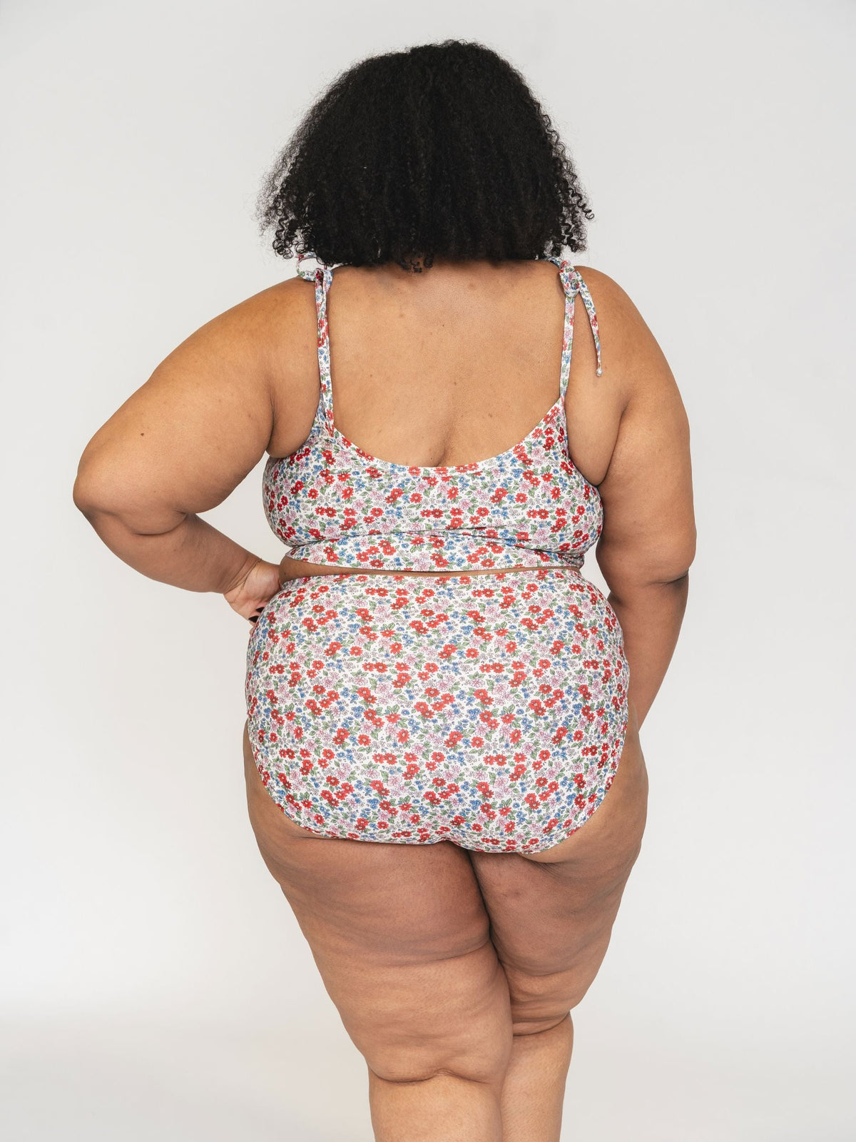 Person wearing a floral swimsuit against a white background