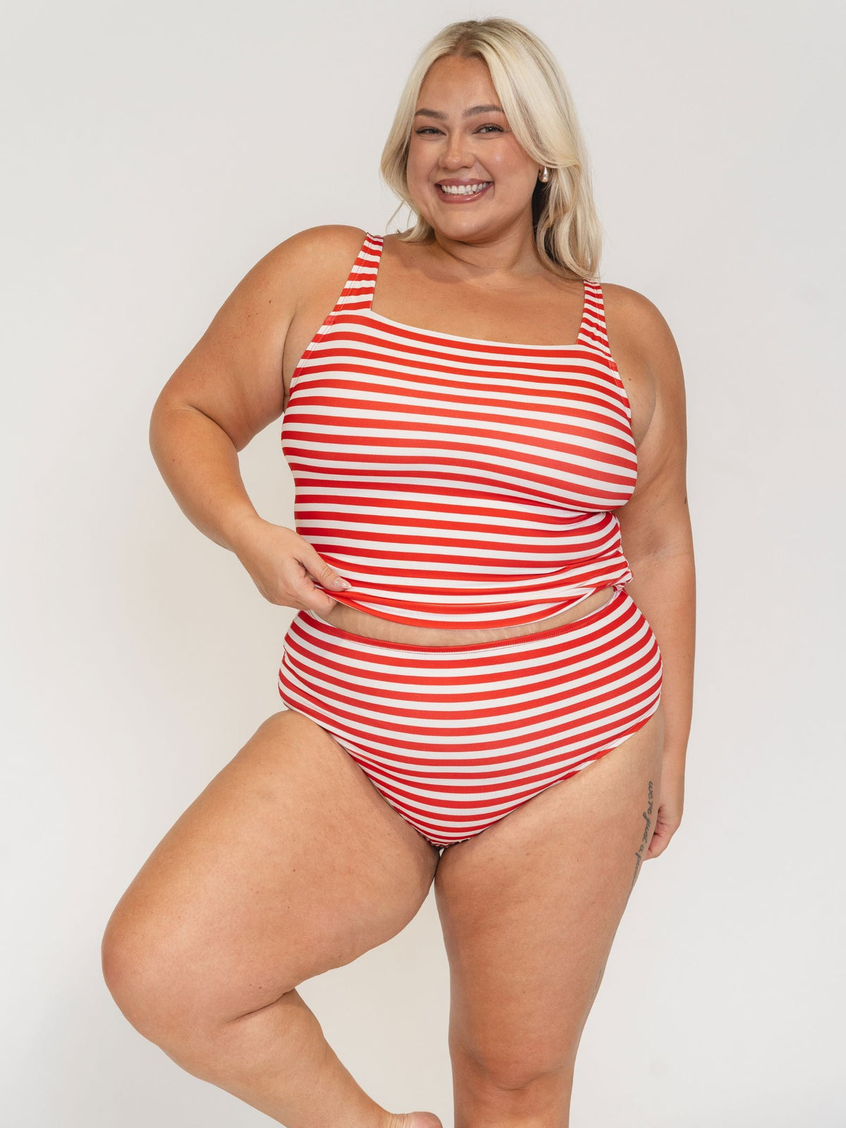 Woman wearing a red and white striped swimsuit on a plain background
