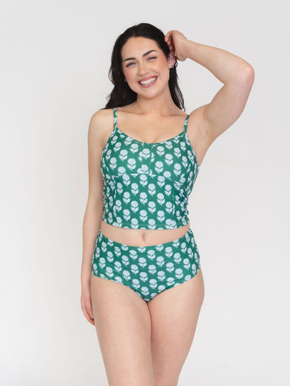 Woman wearing a green patterned two-piece swimsuit on a white background