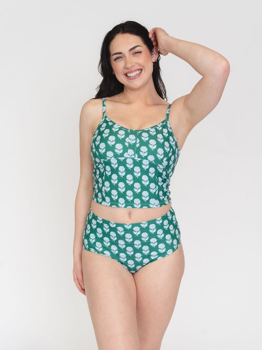 Woman wearing a green patterned two-piece swimsuit on a white background