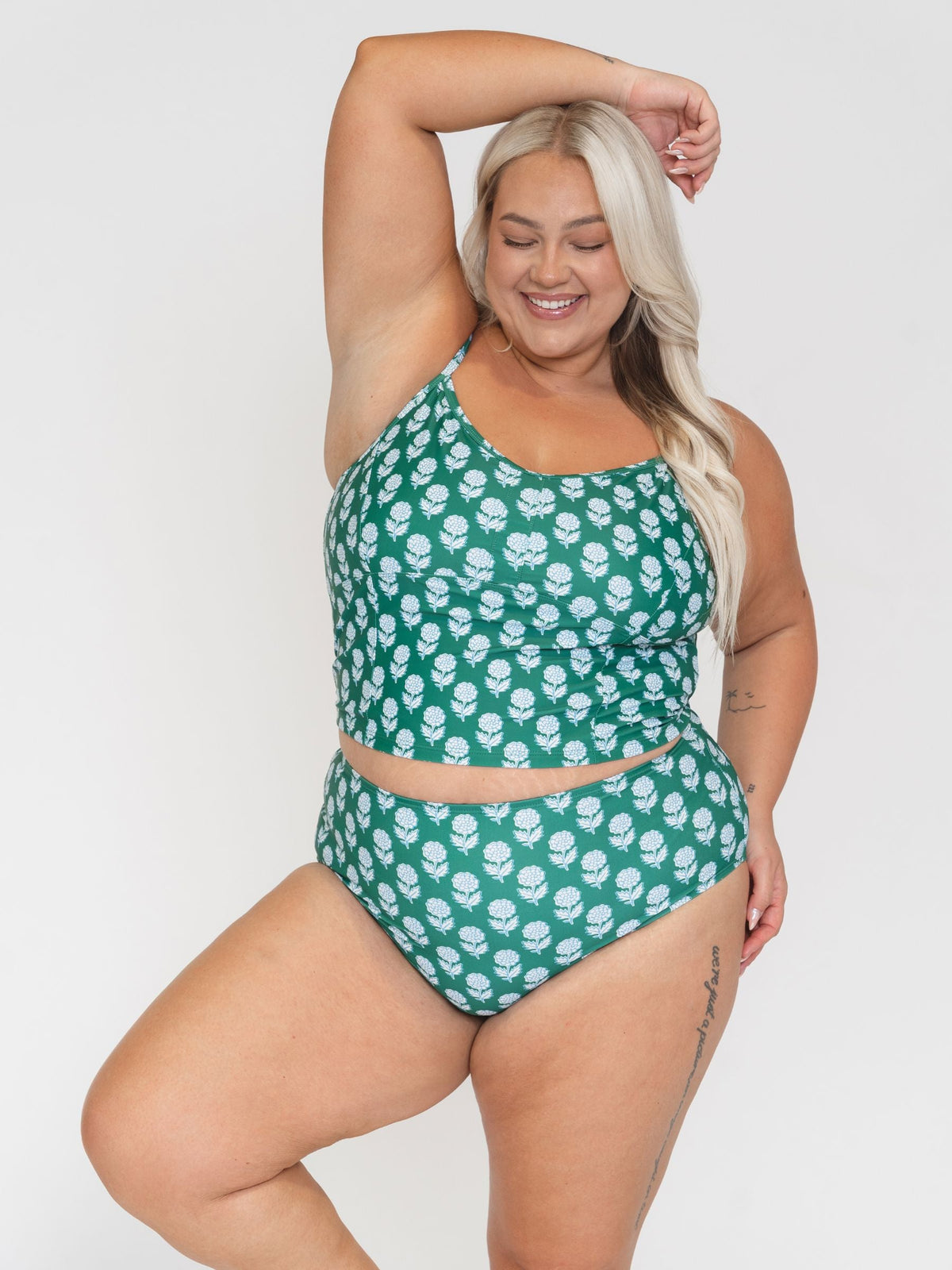 Woman wearing a green and white floral bikini set on a plain background