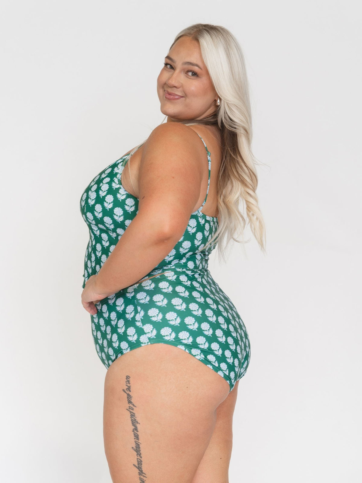 Woman wearing a green floral swimsuit against a white background