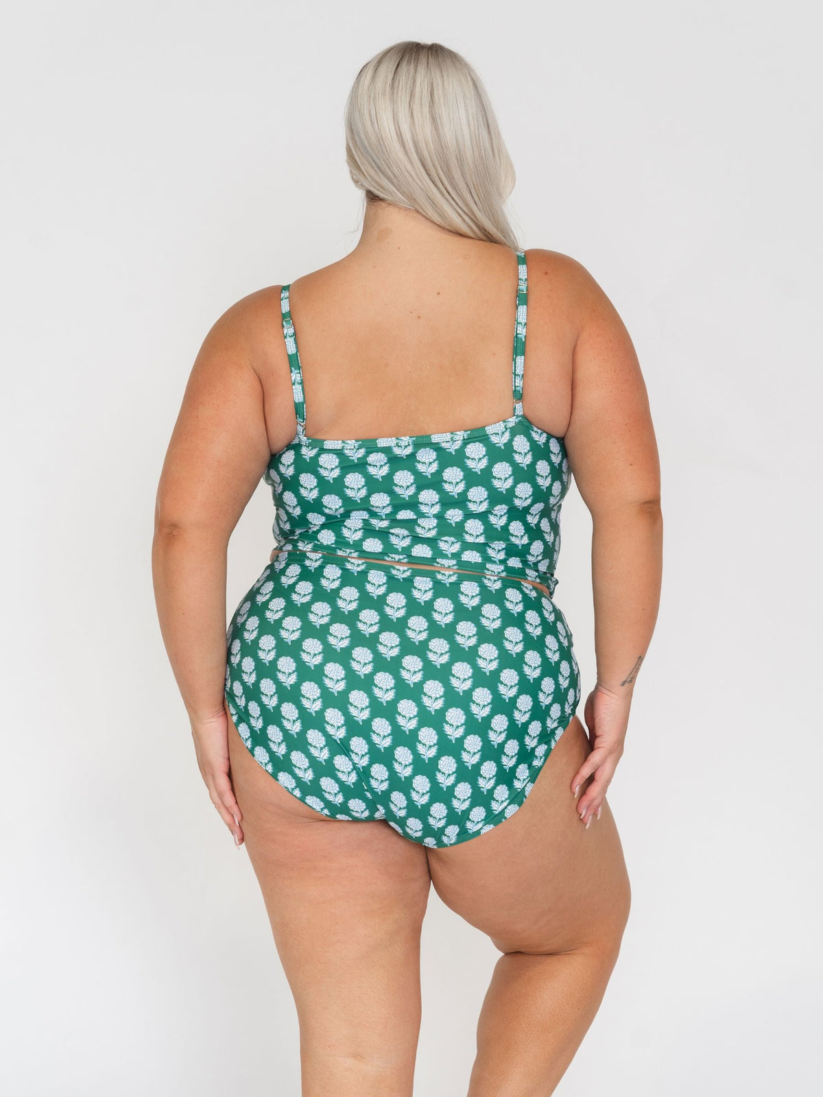 Person wearing a green floral swimsuit against a white background