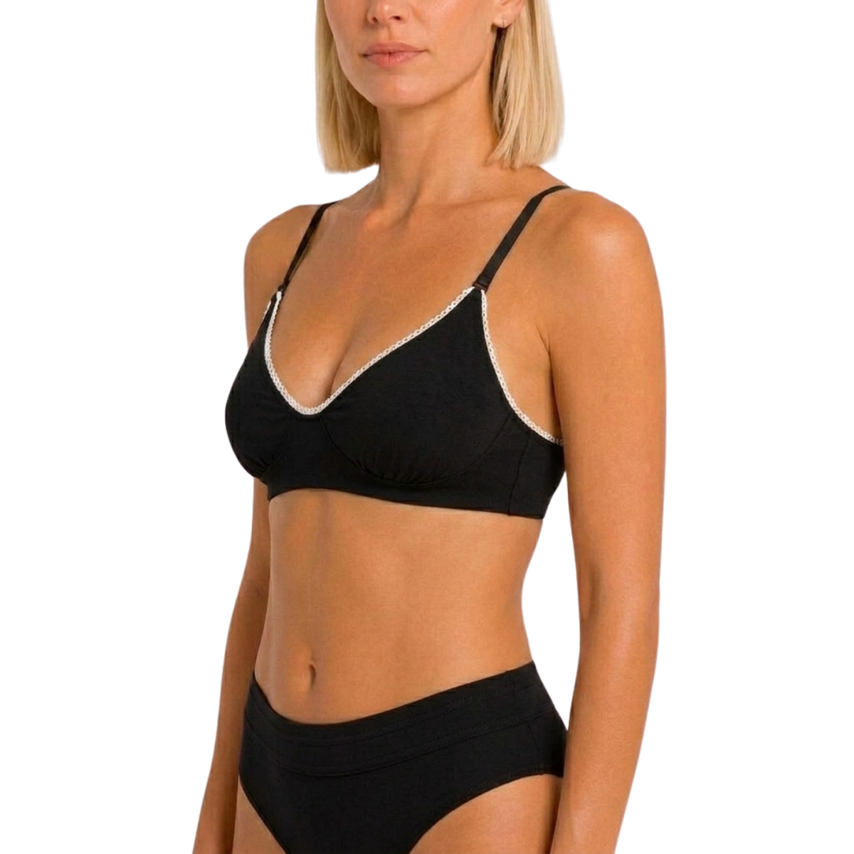 A woman wearing a black bralette with white trim and matching black underwear, shown against a plain white studio background.