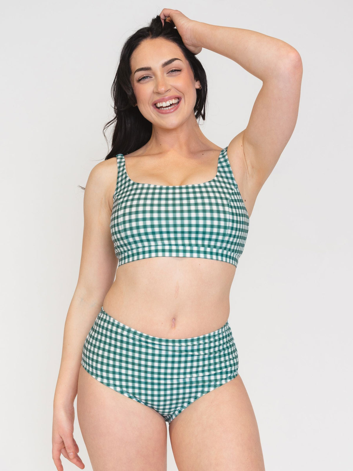 Woman wearing a green and white checkered bikini on a plain background