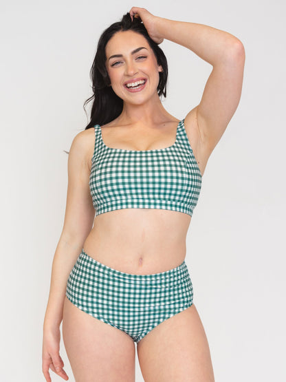 Woman wearing a green and white checkered bikini on a plain background